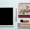 white ipad beside black and pink pen