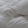 An unmade bed with white sheets and pillows