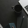 Laptop, mug, and notebooks on a dark workspace