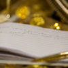 A golden pen rests on a notebook with writing.