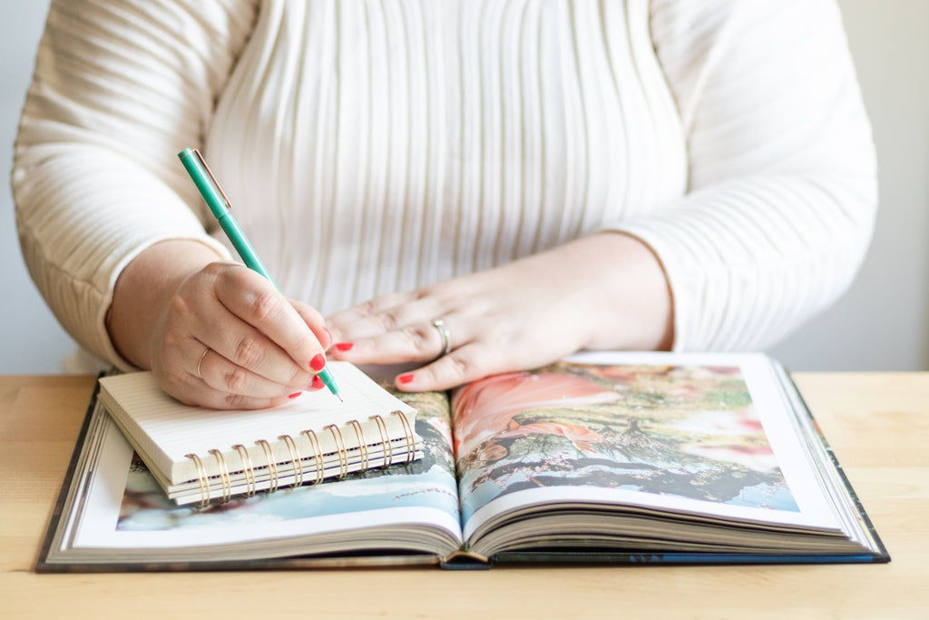 a woman is holding a pen and writing on a book
