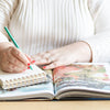a woman is holding a pen and writing on a book