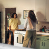 Two women talking in a kitchen while cooking